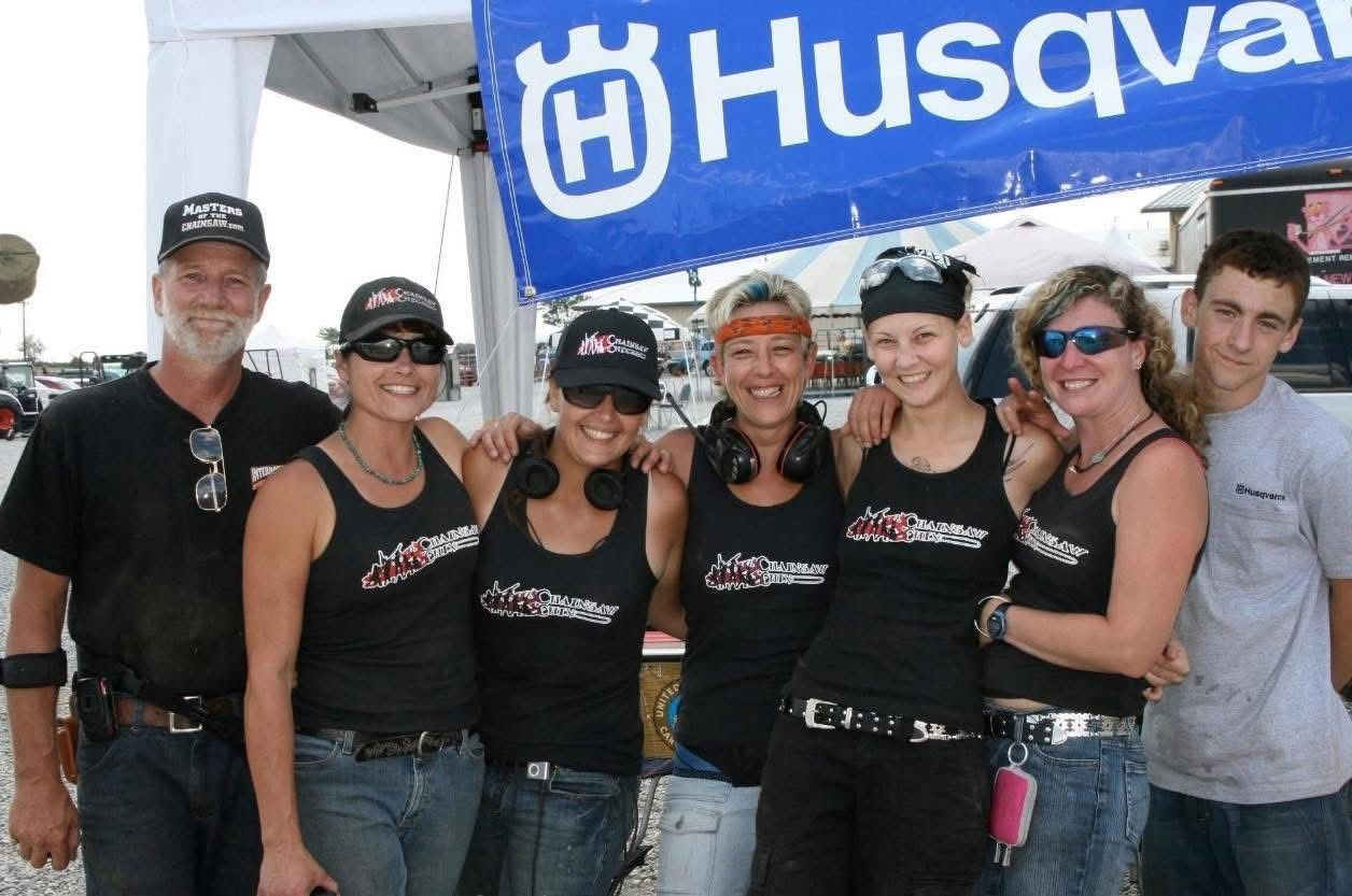 A group of carvers and event crew posing together under an event banner.